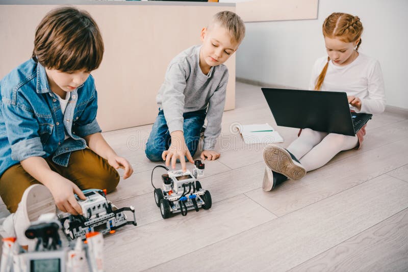 Małe dzieci siedzi na podłoga przy trzon edukaci klasą z robotami fotografia stock