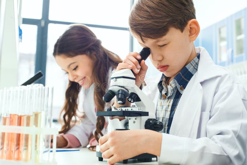 Małe dzieci uczy się chemię w szkolnym laboranckim mikroskopu eksperymencie fotografia stock Małe dzieci uczy się chemię w szkolnym laboranckim mikroskopu eksperymencie fotografia stock