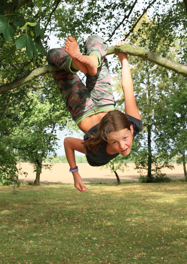 Little kid - strong girl hanging on a thin branch of a tree. Little kid - strong girl hanging on a thin branch of a tree