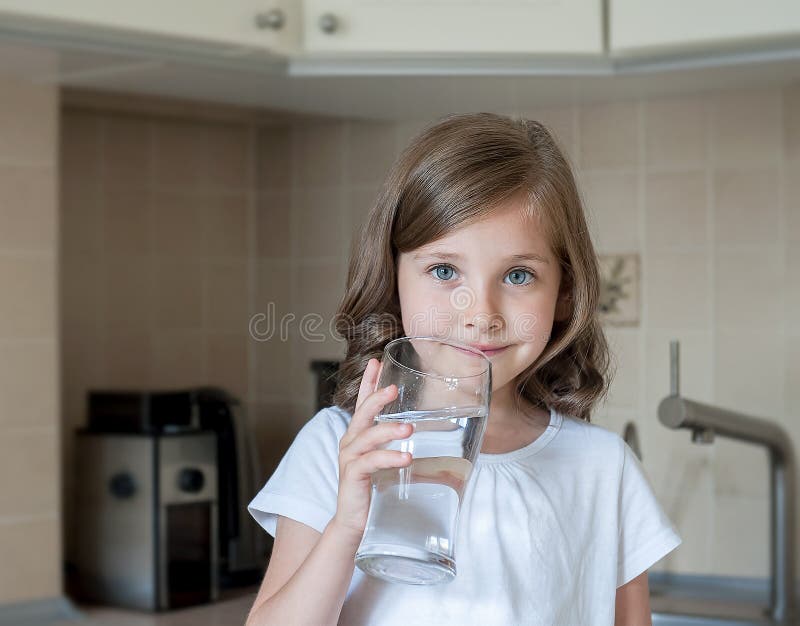 Małe dziecko pije czystą wodę w domu, zakończenie w górę Kaukaska śliczna dziewczyna z długie włosy trzyma wodnego szkło w ona rę obraz stock Małe dziecko pije czystą wodę w domu, zakończenie w górę Kaukaska śliczna dziewczyna z długie włosy trzyma wodnego szkło w ona rę obraz stock