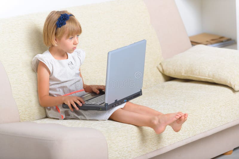 Małej dziewczynki obsiadanie na leżance z laptopem