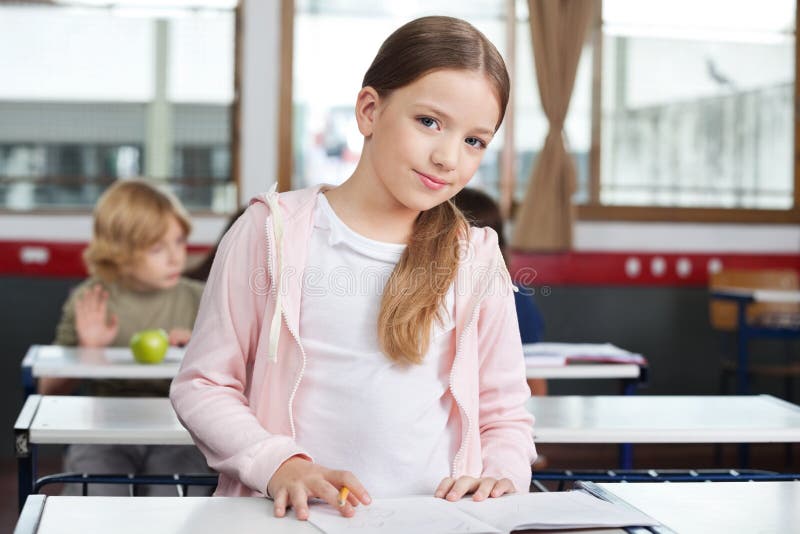 Małej Dziewczynki studiowanie Podczas gdy Stojący Przy biurkiem fotografia stock Małej Dziewczynki studiowanie Podczas gdy Stojący Przy biurkiem fotografia stock