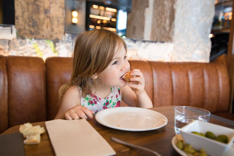 Małej dziewczynki łasowania croquette z ręką w restauraci