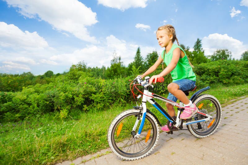 Małej ślicznej dziewczyny jeździeccy dzieci jechać na rowerze na drodze