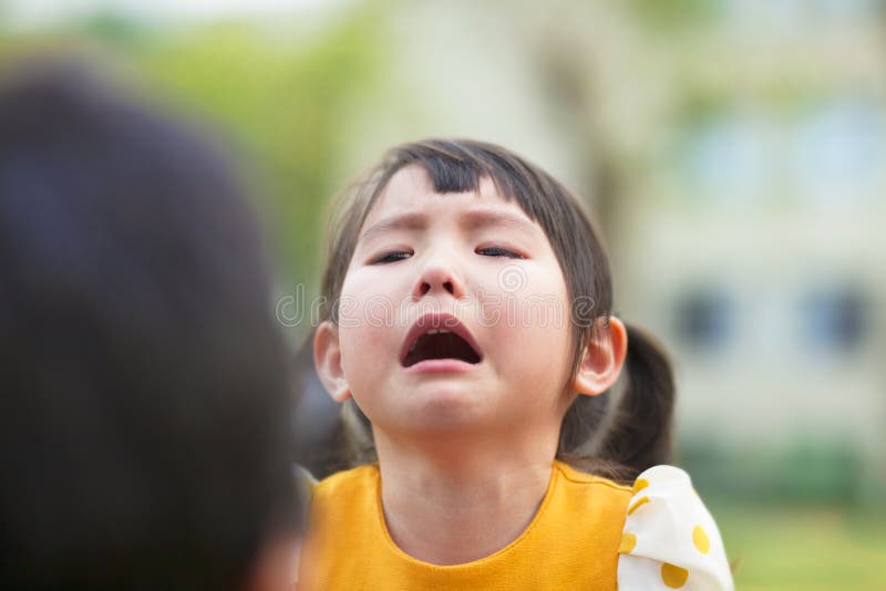 Little asian girl crying and look at her parents in the park. Little asian girl crying and look at her parents in the park