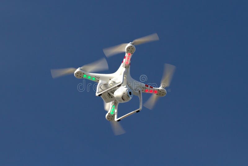 Mały bezpilotowy helikopter z kamerą unosi się w niebie