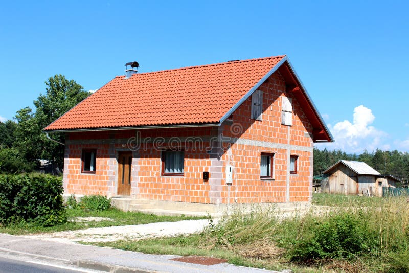 Mały niedokończony ceglany podmiejski rodzina dom z starą drewnianą jatą w tle fotografia stock Mały niedokończony ceglany podmiejski rodzina dom z starą drewnianą jatą w tle fotografia stock