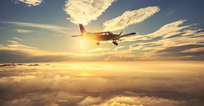 Mały pojedynczego silnika samolotowy latanie w wspaniałym zmierzchu niebie przez morza chmury nad spektakularne góry