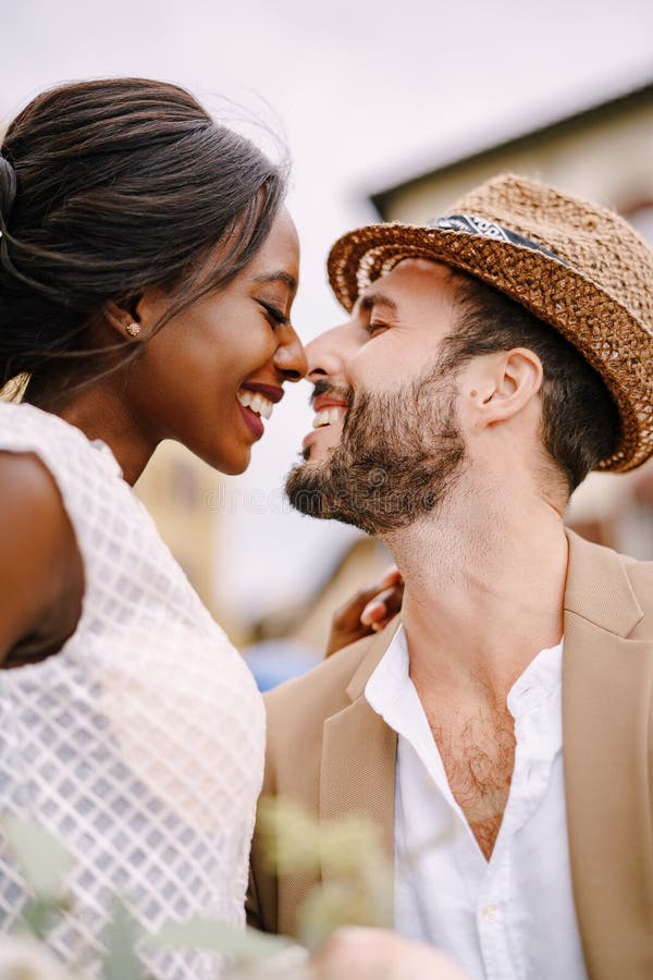 A close-up of portraits of an African-American bride and Caucasian groom in a straw hat. Interracial wedding couple. Wedding in Florence, Italy. A close-up of portraits of an African-American bride and Caucasian groom in a straw hat. Interracial wedding couple. Wedding in Florence, Italy.