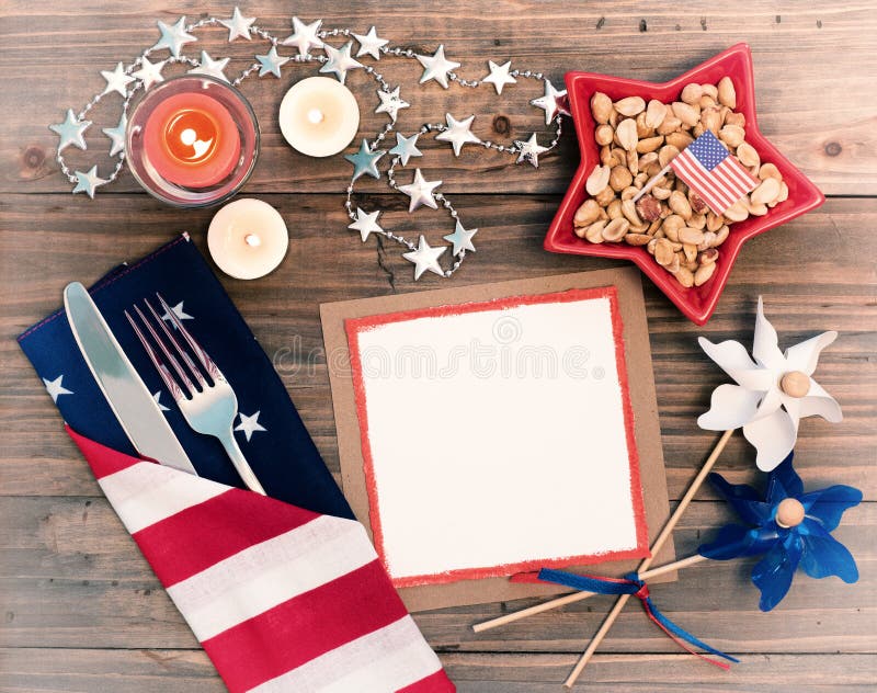 4th of July Table Setting with Flag Napkin, silverware, decorations and a blank white card with space for copy, text or your words. It is a horizontal photo with a faded vintage filter. 4th of July Table Setting with Flag Napkin, silverware, decorations and a blank white card with space for copy, text or your words. It is a horizontal photo with a faded vintage filter