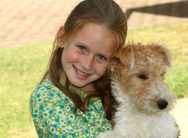 A white caucasian girl child in a green dress holding her puppy. A white caucasian girl child in a green dress holding her puppy