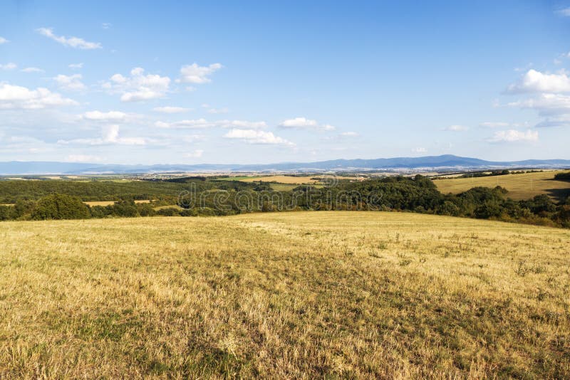 Meadow landscape in the middle of slovakia with blue sky and clouds in autumn fall. Countryside forest with panoramic view on th