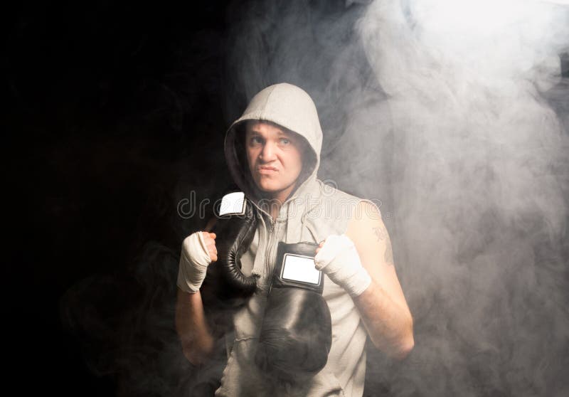 Mean looking ambitious young boxer psyching himself up before a match flexing his fist and snarling in a dark smoky atmosphere. Mean looking ambitious young boxer psyching himself up before a match flexing his fist and snarling in a dark smoky atmosphere