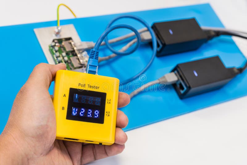 Human palm holding yellow diagnostic digital gauge. Two switched supplies, electric wires and surge protector on blue plastic. Human palm holding yellow diagnostic digital gauge. Two switched supplies, electric wires and surge protector on blue plastic