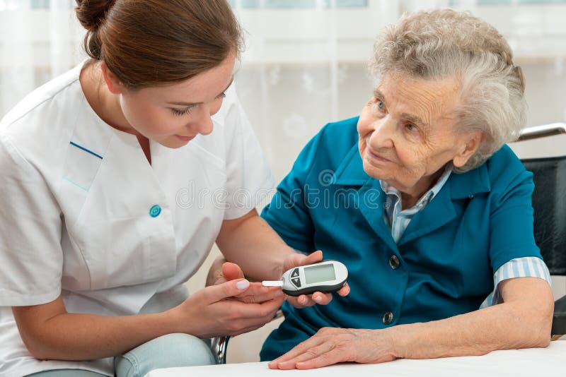 Female nurse measuring blood glucose level of senior woman