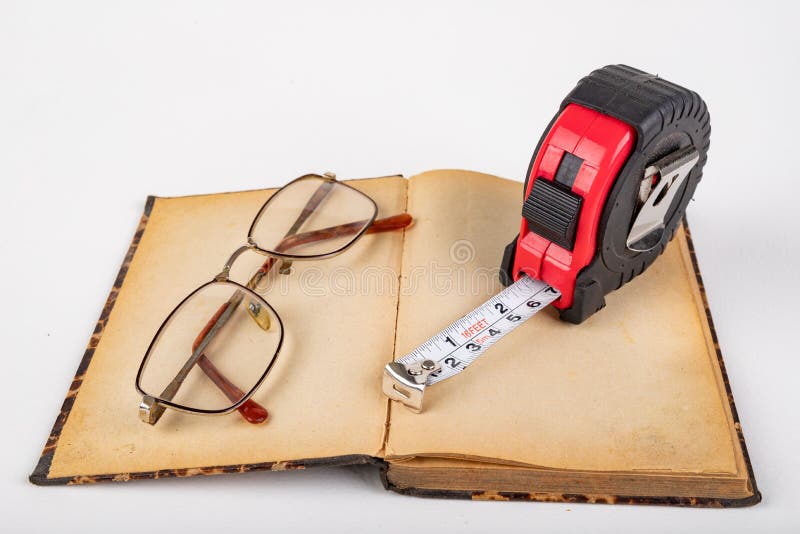 Measuring cup and old book with glasses. Accessories for measurements in carpentry royalty free stock photography Measuring cup and old book with glasses. Accessories for measurements in carpentry royalty free stock photography
