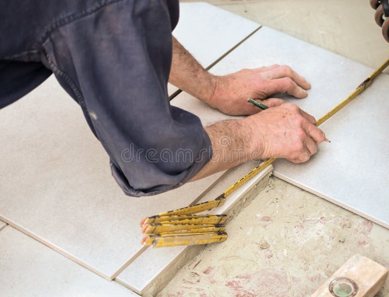 Craftsman is measuring a floor tile with a folding rule