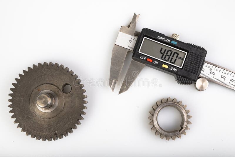 Measuring the gears with a caliper. Engineering work in the laboratory. Light background