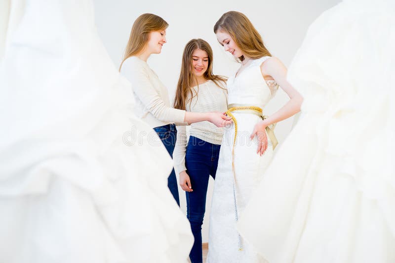 Wedding assistant is measuring the wedding dress. Wedding assistant is measuring the wedding dress