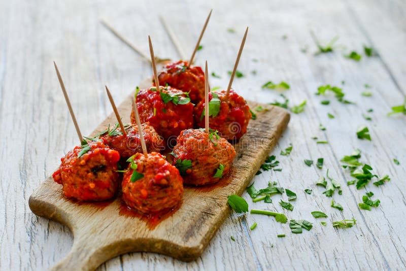 Meat balls with tomato sauce and fresh parsley on cutting board