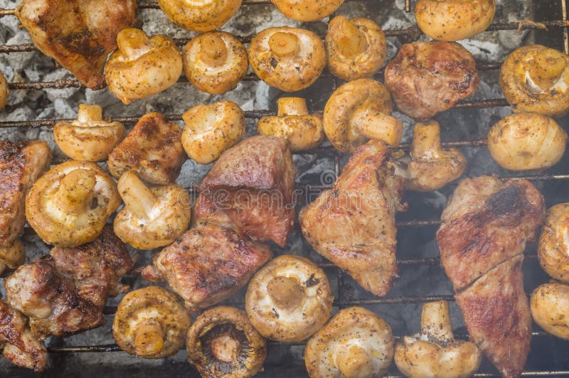 Meat cooking with field mushrooms outdoor on smouldering carbons