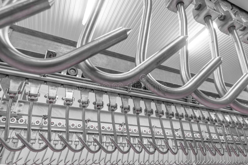 Industrial loading dock area inside cold storage warehouse. Meat hanging hooks hanging on the rail system royalty free stock image