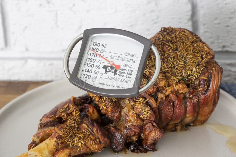 Meat Thermometer Checking Temperature in a Roast Leg of Lamb. Stock