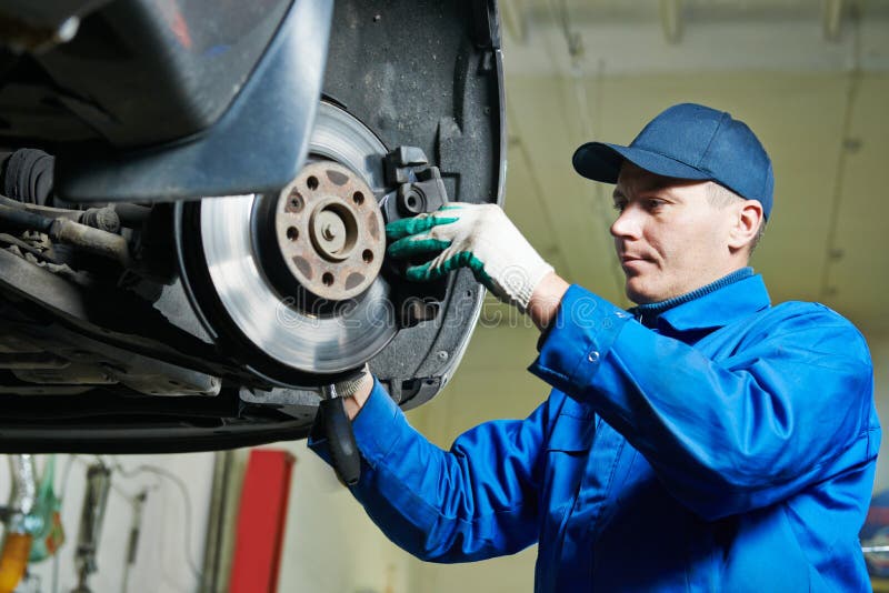 Meccanico alla riparazione della sospensione dell'automobile fotografia stock libera da diritti Meccanico alla riparazione della sospensione dell'automobile fotografia stock libera da diritti