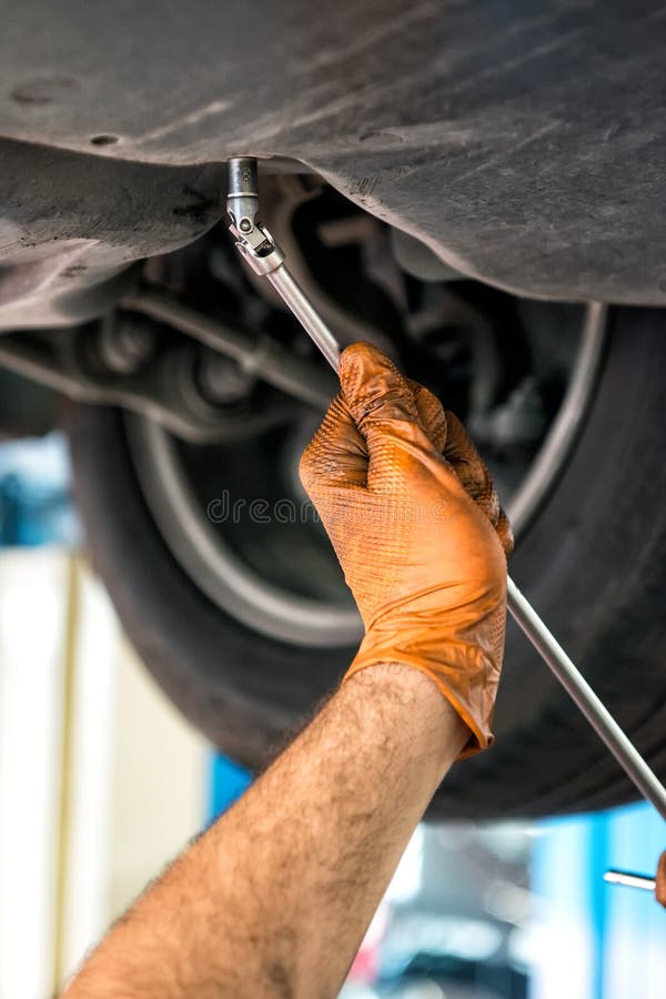 Meccanico che per mezzo di una chiave su un'automobile fotografia stock libera da diritti Meccanico che per mezzo di una chiave su un'automobile fotografia stock libera da diritti