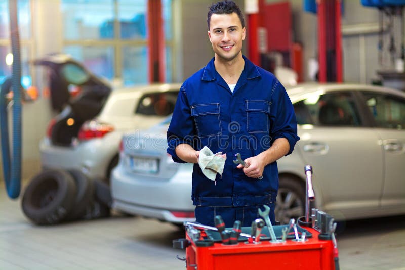 Meccanico di automobile nell'officina riparazioni automatica immagini stock Meccanico di automobile nell'officina riparazioni automatica immagini stock