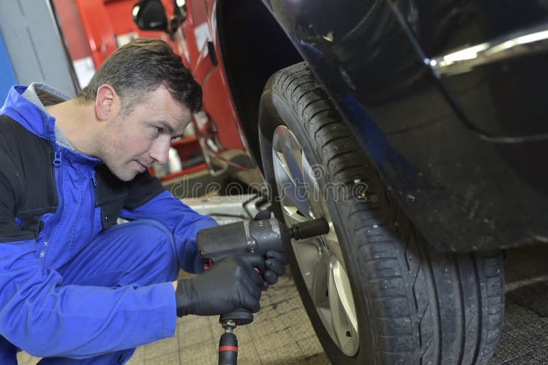 Mechanic changing tire on car