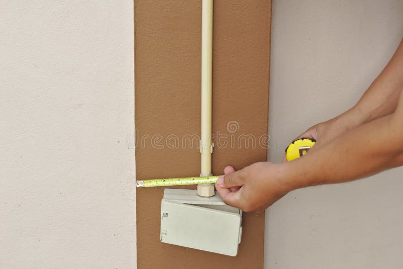 Mechanic checks the height of the switch box after installation. Brown light box on the wall royalty free stock photos
