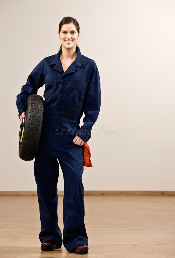 Mechanic in coveralls holding tire