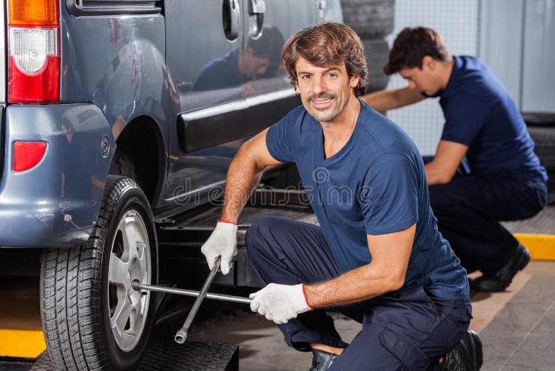 Mechanic Fixing Car Tire At Auto Repair Shop royalty free stock photography Mechanic Fixing Car Tire At Auto Repair Shop royalty free stock photography