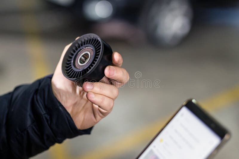 Mechanic hand holding car spare part and ordering new one via smartphone. Vehicle maintenance and service station. Browsing for lowest price through internet. Searching discount and sales.