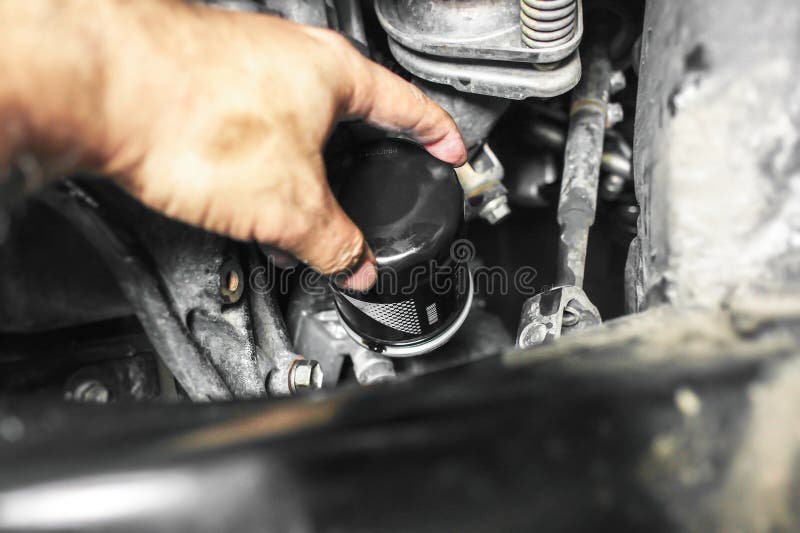 Mechanic hand replacing car oil filter inside engine compartment royalty free stock photo