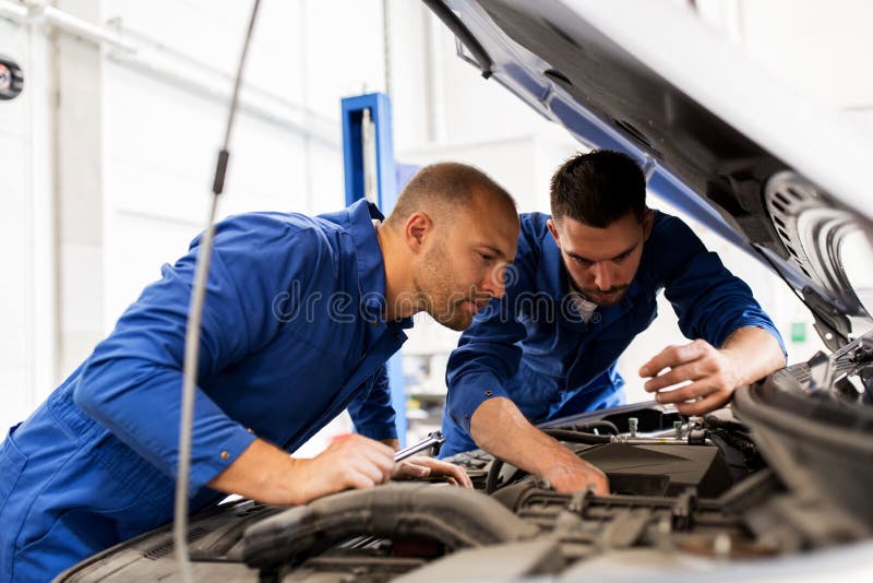 Mechanic men with wrench repairing car at workshop