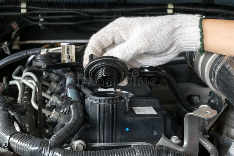 A mechanic is opening the oil cap from a car engine. stock photo