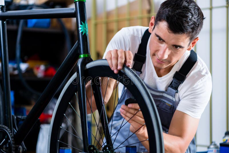 Mechanic repairing bicycle in his workshop stock photos Mechanic repairing bicycle in his workshop stock photos