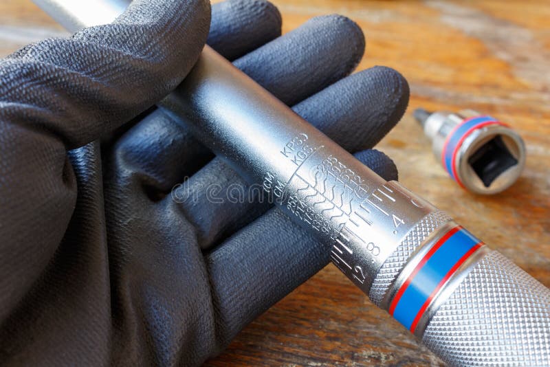 Mechanic`s hand in the working glove holds the torque wrench