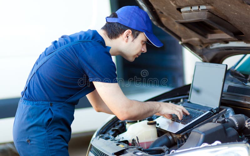 Mechanic using a laptop computer to check a car engine stock images