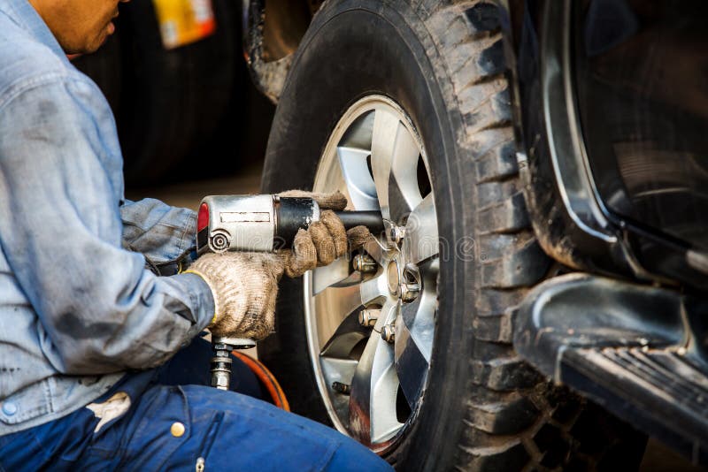 Mechanician changing car wheel in auto repair shop