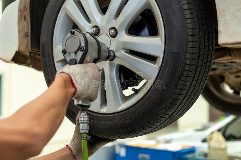 Mechanician changing car wheel in auto repair shop