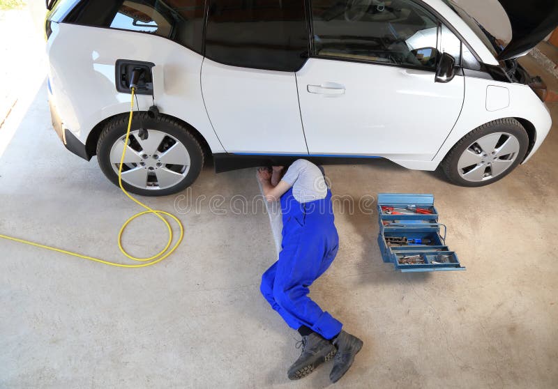 Mechaniker, der ein elektrisches gefahrenes Auto an der Garage repariert stockbilder Mechaniker, der ein elektrisches gefahrenes Auto an der Garage repariert stockbilder