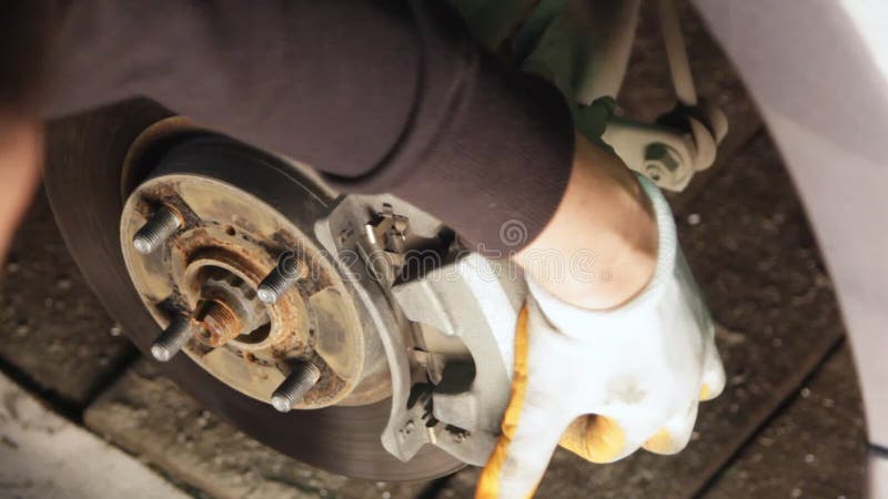 Mecánico de automóviles que trabaja en frenos en un garaje nacional del taller de reparaciones del coche almacen de video