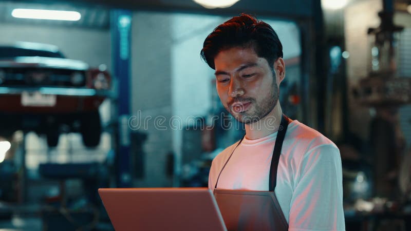 Mecánico en taller de reparación automática con ordenador personal. Hora de la noche almacen de metraje de vídeo