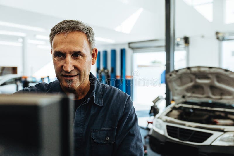 Mecánico que hace diagnóstico del coche en el ordenador fotografía de archivo Mecánico que hace diagnóstico del coche en el ordenador fotografía de archivo