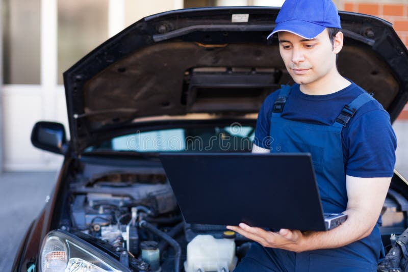 Mecánico que usa un ordenador portátil para comprobar un motor de coche imagenes de archivo Mecánico que usa un ordenador portátil para comprobar un motor de coche imagenes de archivo