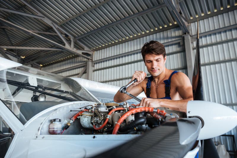 Mecânico de aviões novo sério que fixa o avião pequeno imagem de stock Mecânico de aviões novo sério que fixa o avião pequeno imagem de stock