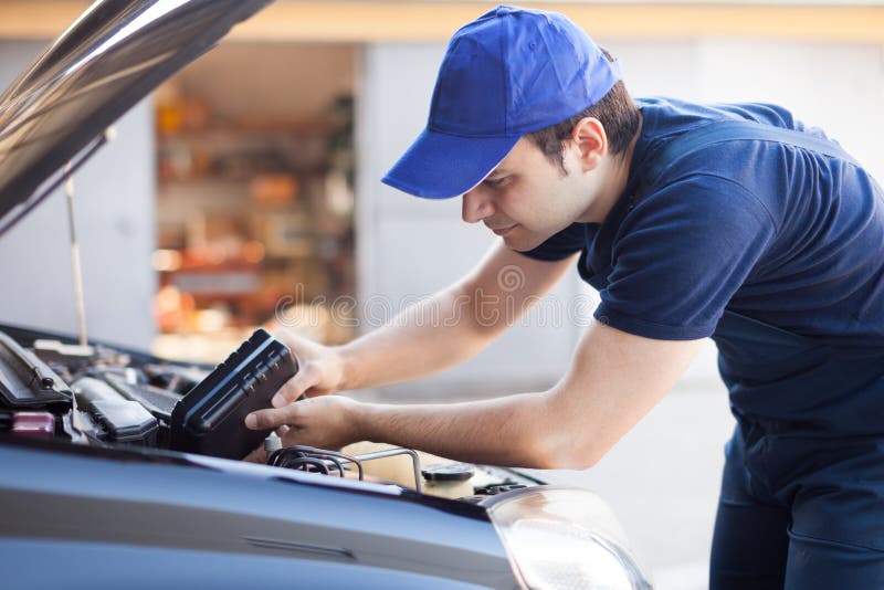 Mecânico que presta serviços de manutenção a um motor de automóveis foto de stock Mecânico que presta serviços de manutenção a um motor de automóveis foto de stock